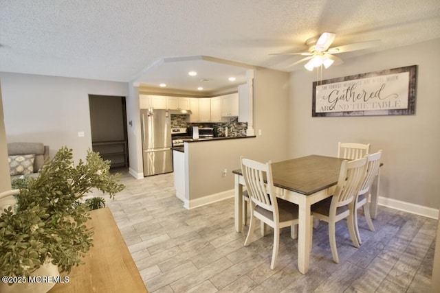 dining space with ceiling fan, a textured ceiling, light wood-type flooring, and baseboards