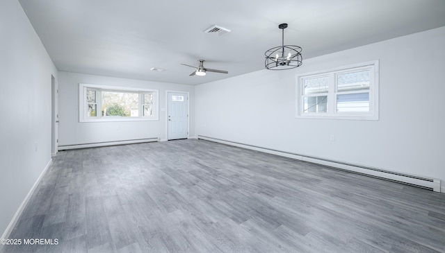 spare room with a baseboard radiator, a baseboard heating unit, wood finished floors, visible vents, and baseboards