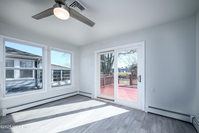 unfurnished room with visible vents, baseboard heating, a baseboard heating unit, a ceiling fan, and wood finished floors