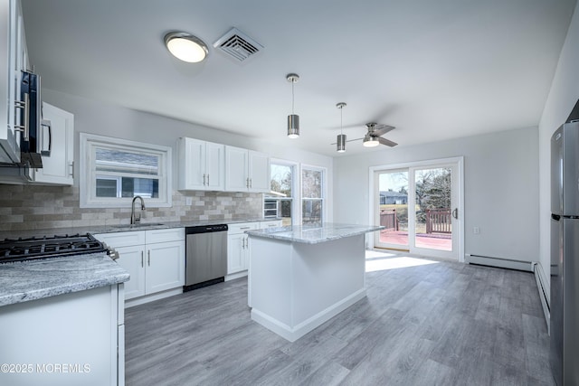 kitchen featuring visible vents, decorative backsplash, light stone countertops, stainless steel appliances, and a sink