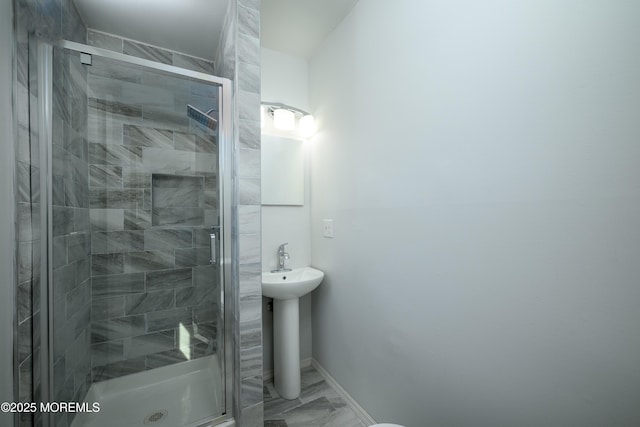 bathroom with marble finish floor, baseboards, and a stall shower