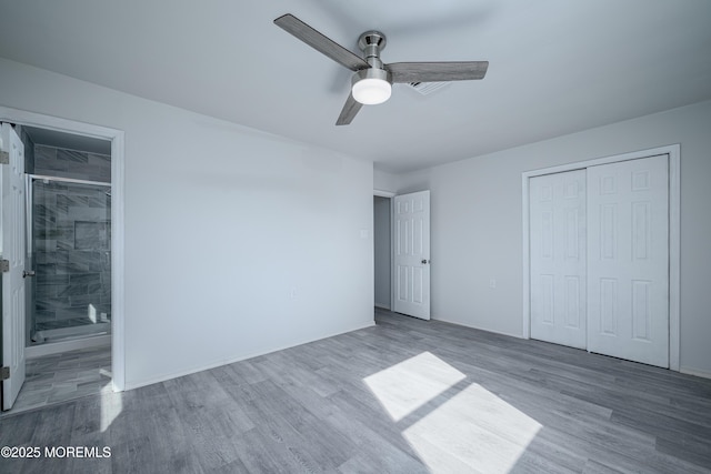 unfurnished bedroom featuring connected bathroom, a closet, a ceiling fan, and wood finished floors