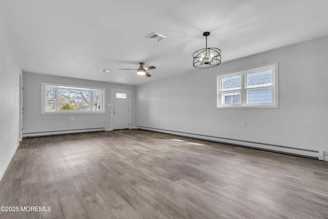 unfurnished living room featuring a baseboard heating unit, ceiling fan with notable chandelier, wood finished floors, and visible vents