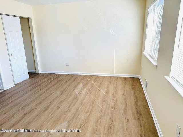 spare room featuring baseboards, visible vents, and light wood-style floors