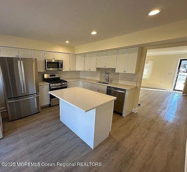 kitchen with white cabinets, a kitchen island, appliances with stainless steel finishes, light countertops, and a sink