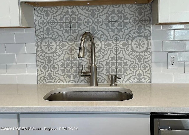 details featuring white cabinets, a sink, and light countertops