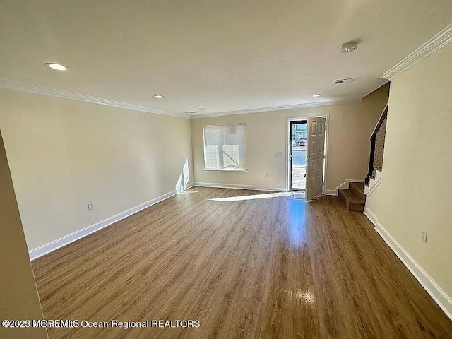 unfurnished living room with crown molding, stairway, wood finished floors, and baseboards