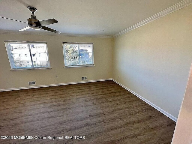 empty room with baseboards, dark wood-type flooring, visible vents, and crown molding