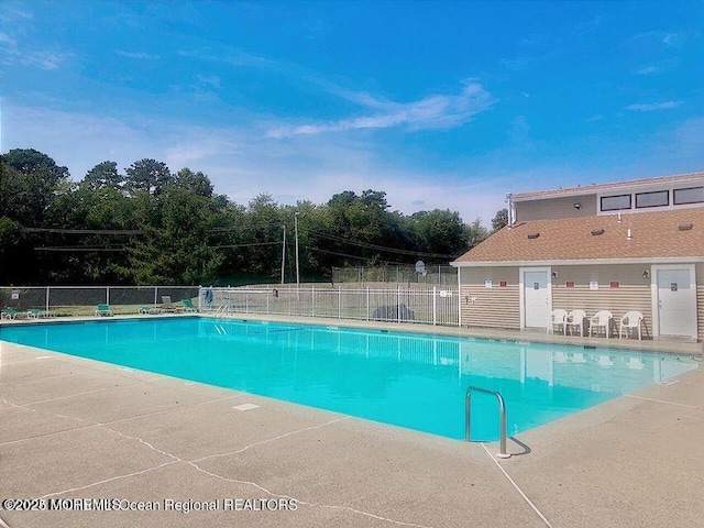 pool with a patio area and fence