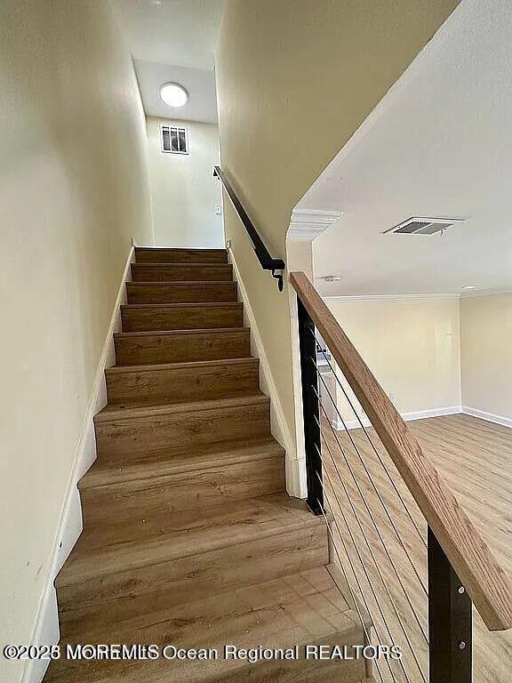 stairway featuring wood finished floors and visible vents