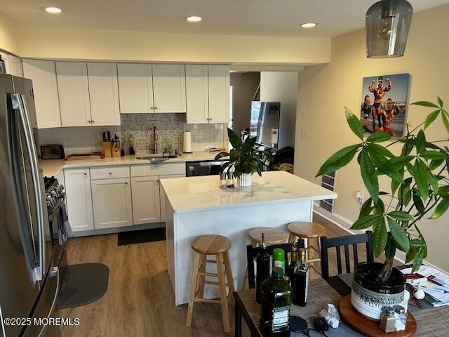 kitchen with a center island, freestanding refrigerator, light countertops, white cabinetry, and a sink