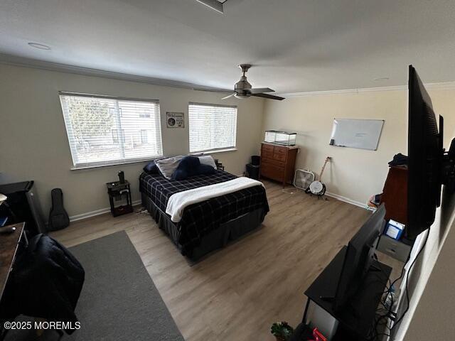 bedroom featuring a ceiling fan, light wood-style flooring, baseboards, and crown molding