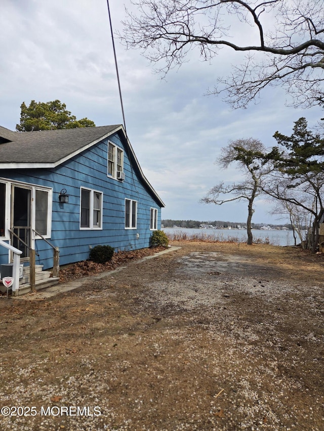 view of property exterior with a shingled roof and a water view