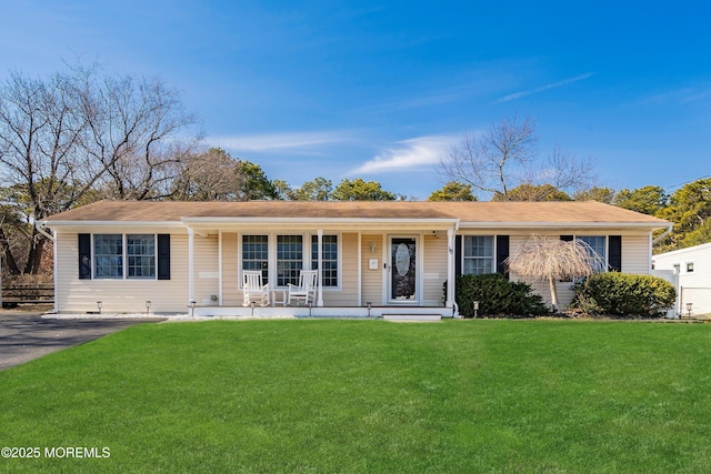 ranch-style home featuring covered porch and a front lawn