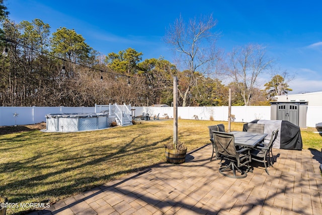 view of patio / terrace with a storage shed, outdoor dining space, a fenced backyard, and a fenced in pool