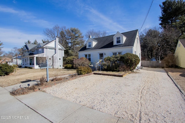 view of front of house with driveway, fence, and roof with shingles