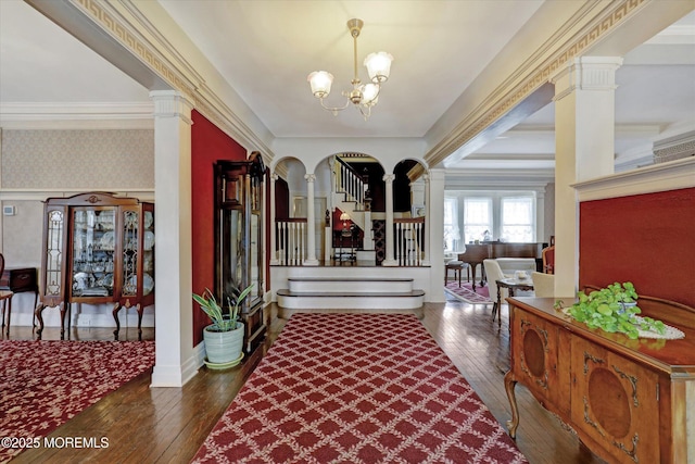 foyer with stairs, ornamental molding, wallpapered walls, hardwood / wood-style floors, and ornate columns