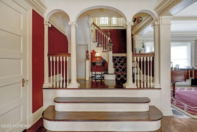 stairway with wood finished floors, decorative columns, and baseboards