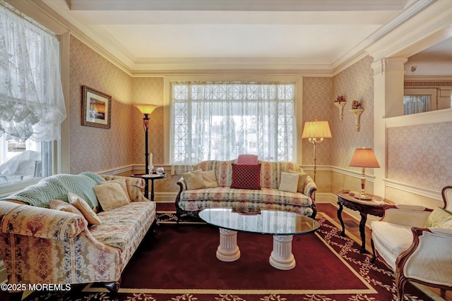 living room featuring ornate columns, ornamental molding, wood finished floors, and wallpapered walls