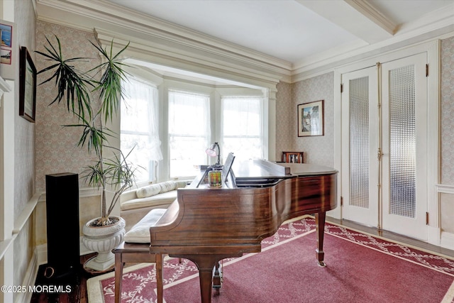 living area featuring wallpapered walls, wood finished floors, crown molding, and a wainscoted wall