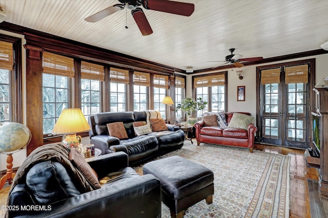 living room with a ceiling fan, wood finished floors, crown molding, and french doors