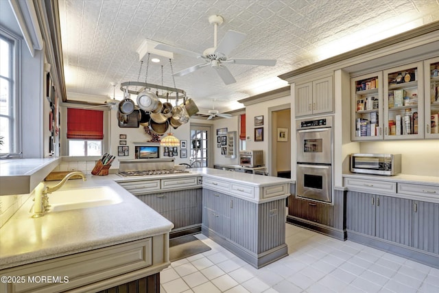 kitchen with an ornate ceiling, ornamental molding, a peninsula, stainless steel appliances, and a sink