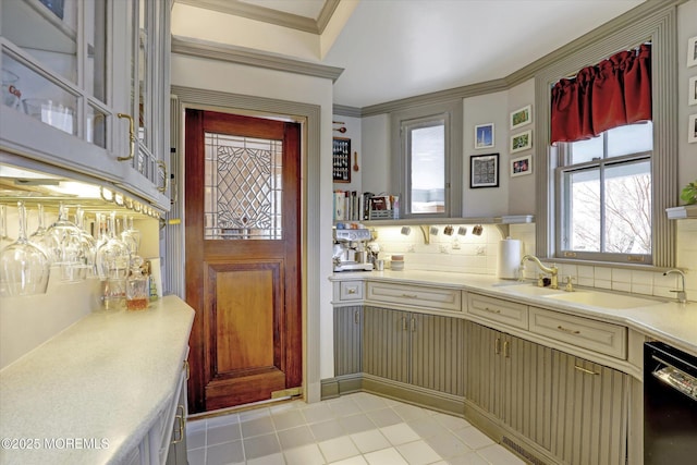 kitchen with black dishwasher, light countertops, cream cabinetry, crown molding, and backsplash