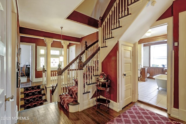 stairs with decorative columns, baseboards, and wood finished floors