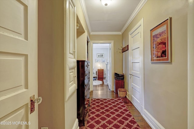 hallway with ornamental molding, dark wood finished floors, and baseboards