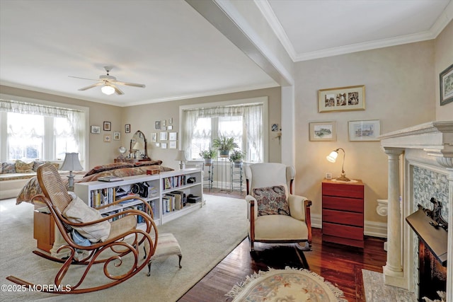 sitting room with wood finished floors, ornamental molding, a fireplace with flush hearth, and a healthy amount of sunlight