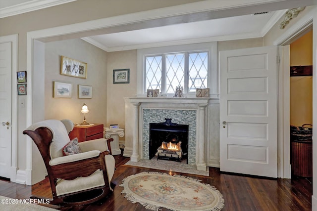 sitting room with ornamental molding, a premium fireplace, and wood finished floors