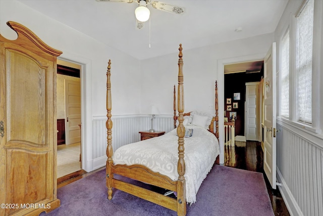 bedroom with a ceiling fan and wainscoting