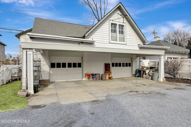 view of property exterior with a garage, roof with shingles, and fence