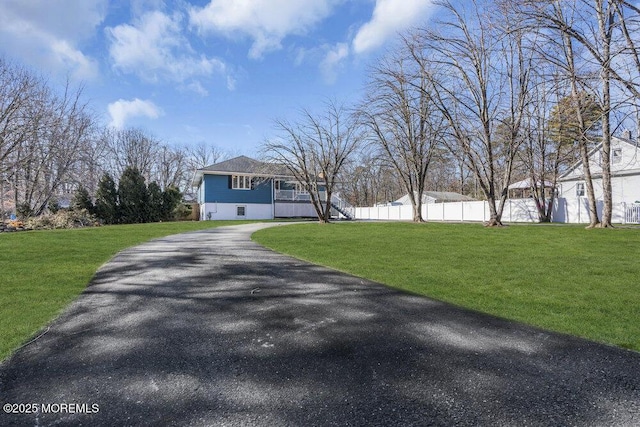 view of front of house featuring driveway, a front lawn, and fence