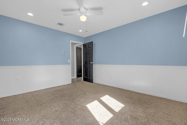 empty room with recessed lighting, visible vents, a ceiling fan, wainscoting, and carpet flooring