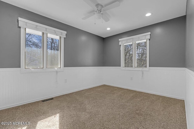 carpeted empty room with recessed lighting, a wainscoted wall, visible vents, and ceiling fan