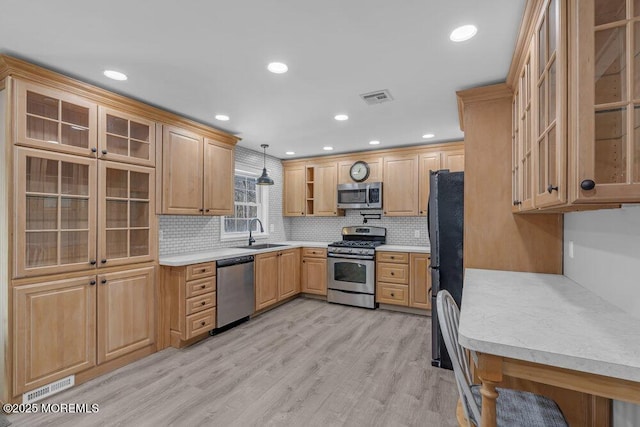 kitchen with stainless steel appliances, light countertops, visible vents, light wood-style flooring, and a sink