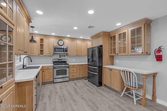 kitchen featuring visible vents, stainless steel appliances, light countertops, light wood-type flooring, and a sink