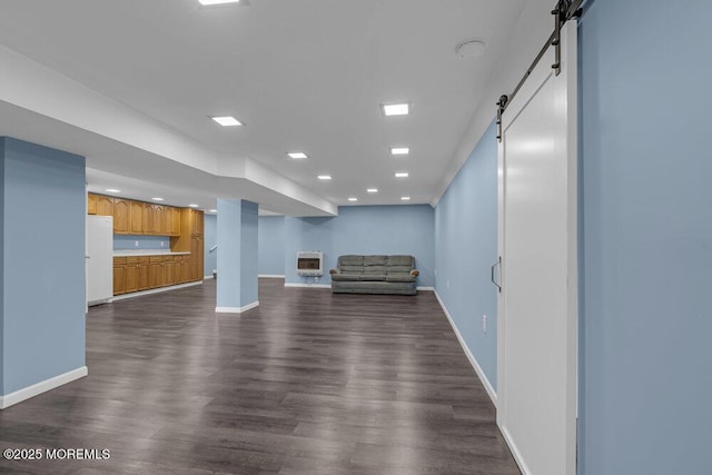 unfurnished living room featuring a barn door, recessed lighting, baseboards, heating unit, and dark wood-style floors