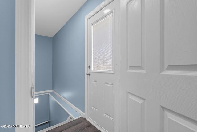 doorway featuring dark wood-style flooring and baseboards