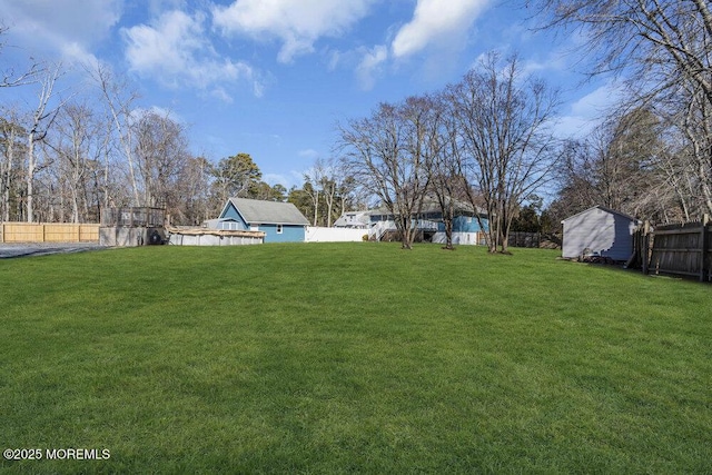 view of yard with a fenced backyard, a shed, and an outdoor structure