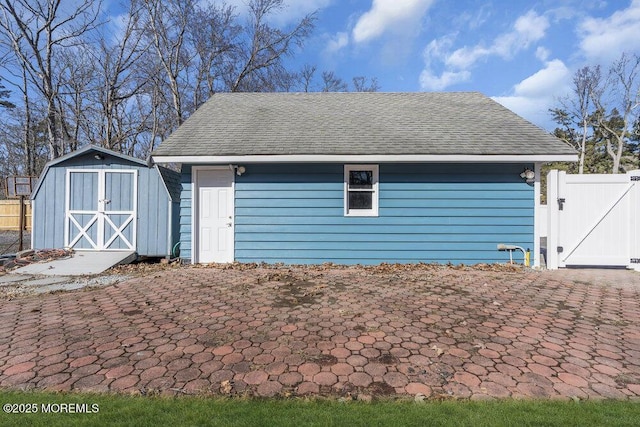 garage featuring a gate, a storage unit, and fence