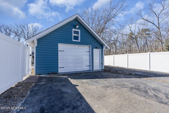 detached garage with aphalt driveway and fence