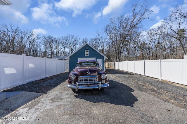 view of parking featuring a fenced backyard, a detached garage, and driveway