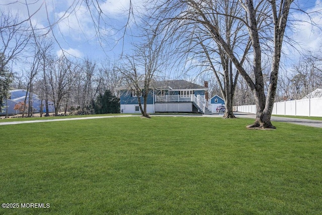 view of front facade featuring covered porch, stairs, fence, and a front yard