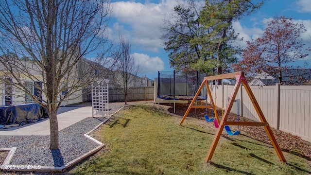 communal playground featuring a yard, a trampoline, and a fenced backyard