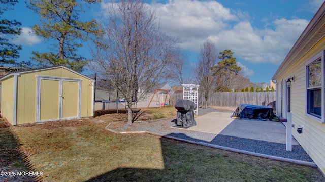 view of yard featuring an outbuilding, a fenced backyard, a shed, a trampoline, and a patio area