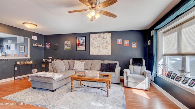 living room with a ceiling fan, baseboards, and wood finished floors