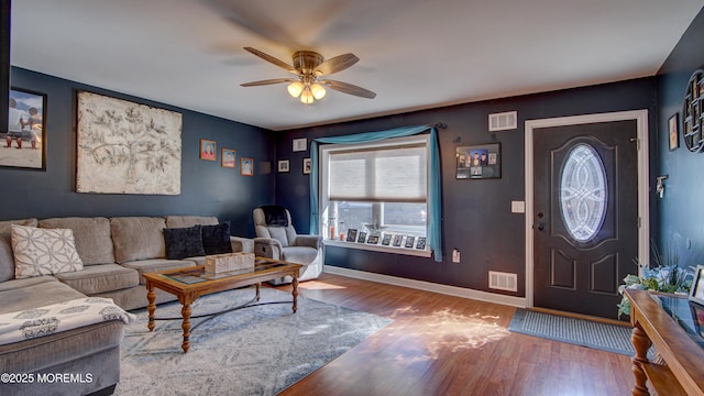 living area featuring visible vents, ceiling fan, baseboards, and wood finished floors