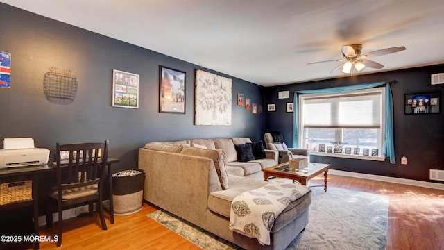 living room featuring a ceiling fan, visible vents, baseboards, and wood finished floors